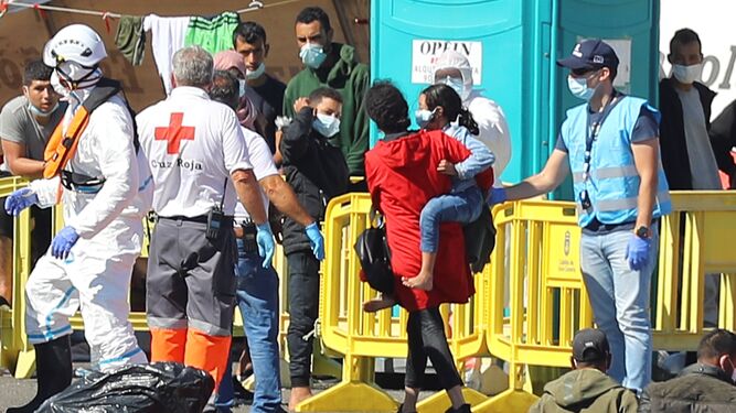 Miembros de la Cruz Roja ayudan a los inmigrantes recluidos en el muelle de Arguenaguín.