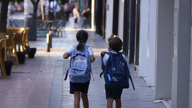 Dos escolares cargan con sus mochilas.
