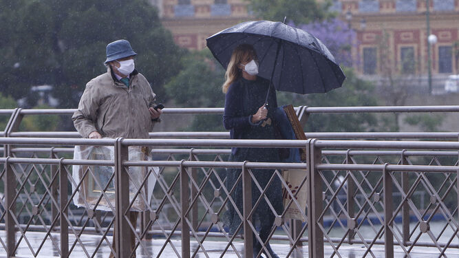 Dos personas pasean bajo la lluvia en Sevilla.