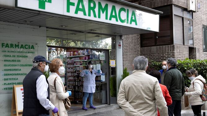 Varias personas esperan su turno en la puerta de una farmacia.