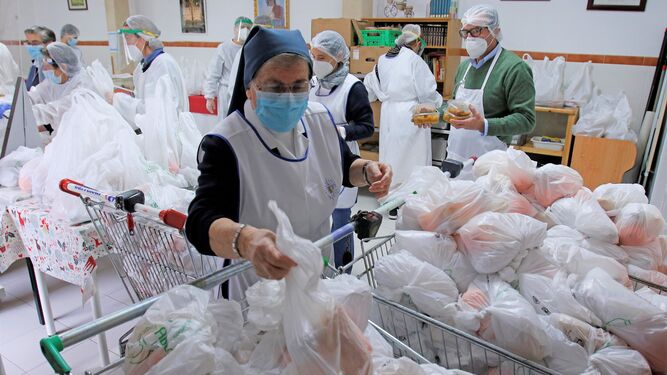 Voluntarios, profesionales y hermanas organizan la comida en bolsas para el reparto.