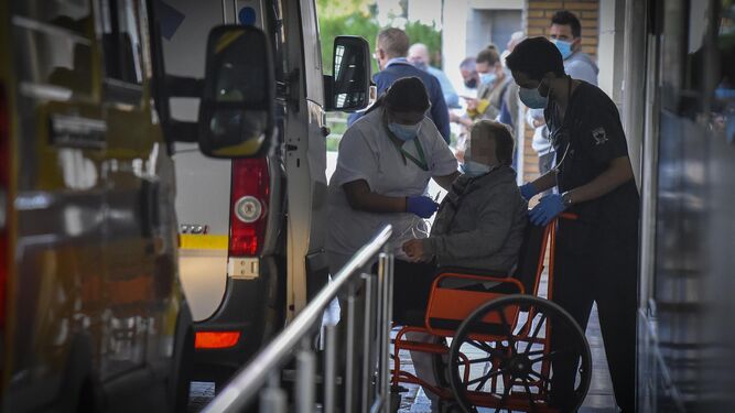 Sanitarios sacan en silla de ruedas a una pacientes en Urgencias del Virgen Macarena.