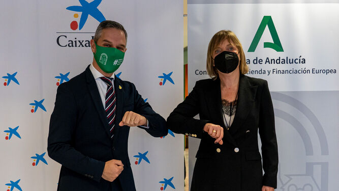 El consejero de Hacienda y Financiación Europea, Juan Bravo, y la directora territorial de Caixabank en Andalucía Occidental, María Jesús Catalá.