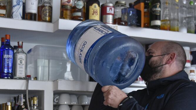 El propietario de un bar prepara la cafetera con agua de un camión cisterna.
