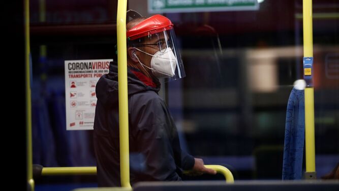Un pasajero protegido con mascarilla y pantalla viaja en un autobús de Madrid.
