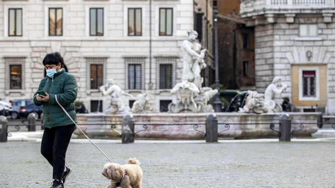 Una mujer pasea a su perro por el centro de Roma.