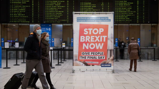 Viajeros pasan ante un cartel contra el Brexit en una estación de Bruselas.