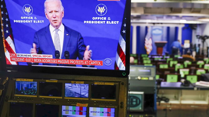 Una televisión muestra a Joe Biden; al fondo, la sala de prensa de la Casa Blanca.