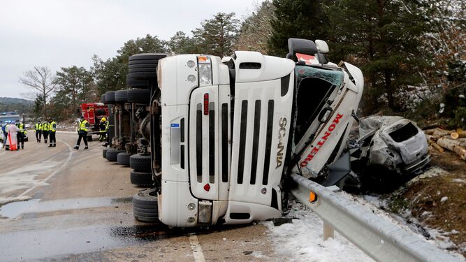 Un camión cargado de troncos volcado sobre un coche en una carretera de Soria.