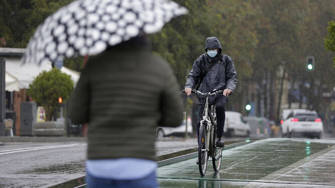 Un ciclista con mascarilla bajo la lluvia.