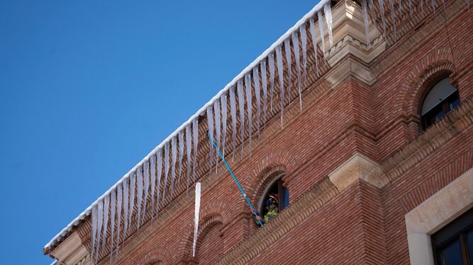 Un bombero retira carámbanos de hielo de la cornisa de un edificio en Teruel.