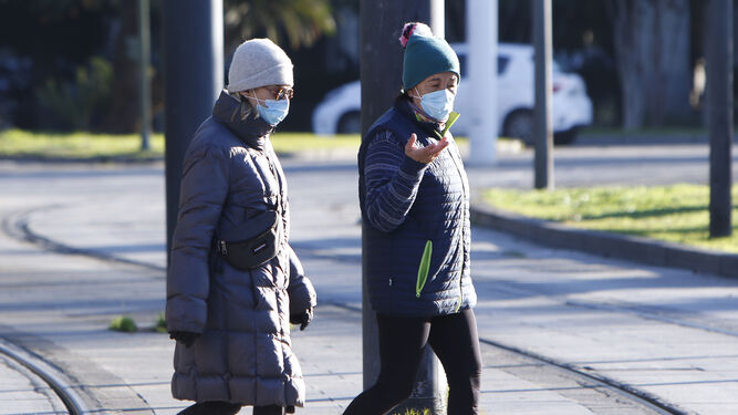 Dos personas pasean protegidas del frío.
