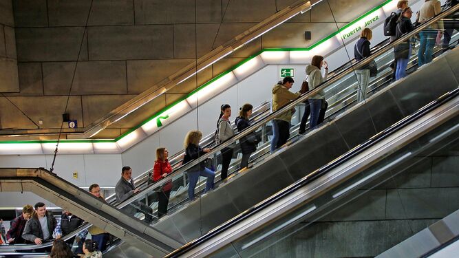 Viajeros subiendo por la escalera mecánica de la estación subterránea Puerta de Jerez.