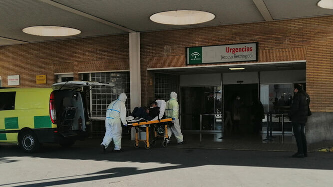 Dos sanitarios bajan en camilla a un paciente a las puertas de Urgencias del Hospital Virgen del Rocío.