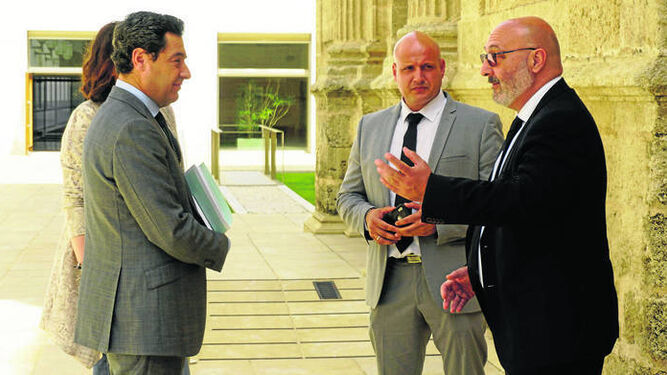 El portavoz parlamentario de Vox Andalucía, Alejandro Hernández, conversa con el presidente de la Junta, Juanma Moreno, en el exterior de la sala del Pleno de la Cámara.