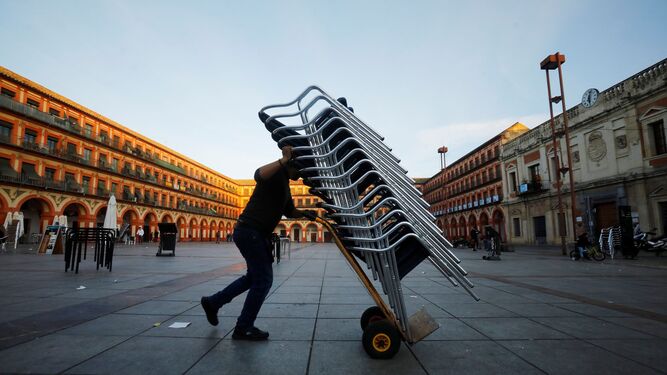 Un trabajador de la hostelería recoge su terraza de su bar a las seis de la tarde  en Córdoba.