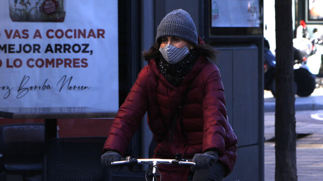 Una joven en bicicleta protegida del frío.