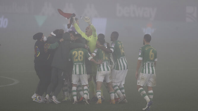 Los futbolistas del Betis celebran el triunfo eufóricos entre la niebla.
