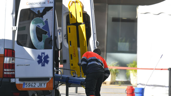 Un sanitario metiendo una camilla en una ambulancia frente a un centro hospitalario andaluz