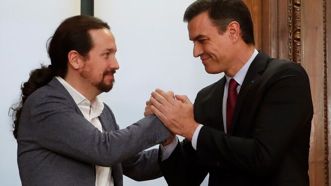 Pablo iglesias y Pedro Sánchez estrechan sus manos tras la firma del acuerdo programático de gobierno.
