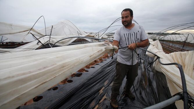 Imagen de archivo en la que un hombre trata de arreglar algunos de los daños  en un invernadero, en la zona de Valdeflores, en Cartaya (Huelva).