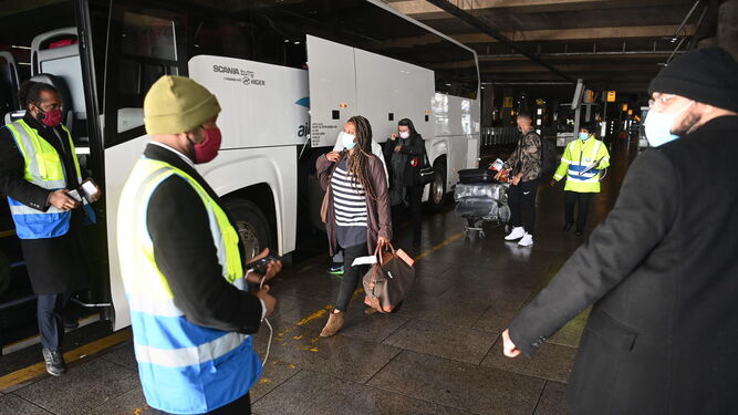 Viajeros llegados al aeropuerto de Heathrow son acompañados en su traslado al hotel donde guardarán la cuarentena.