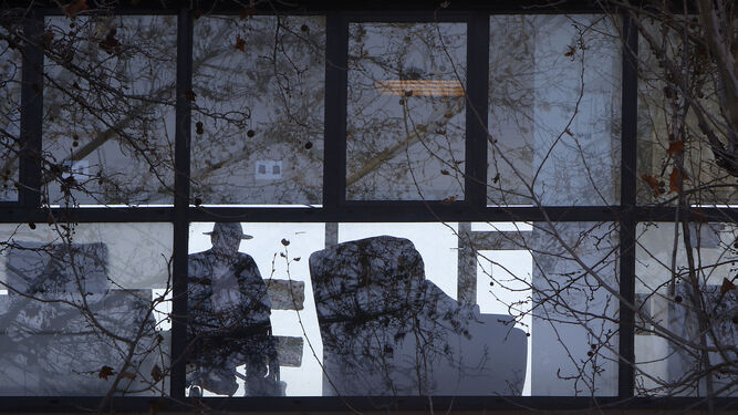 Un anciano mira al exterior tras la cristalera de un centro de mayores.