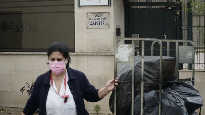 Una trabajadora saca bolsas edificio de la residencia y de la unidad de estancia diurna de Asisttel en Tomares, ya desalojado.