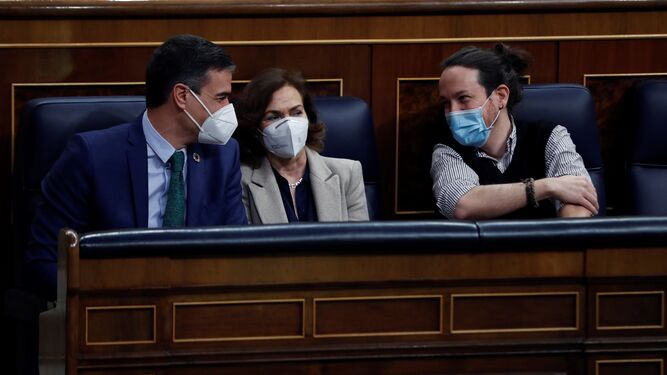 El presidente del Gobierno, Pedro Sánchez, conversa con sus vicepresidentes Carmen Calvo, y Pablo Iglesias, en el Congreso este miércoles.