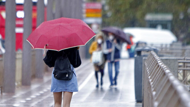 Una joven camina por Sevilla con paraguas.