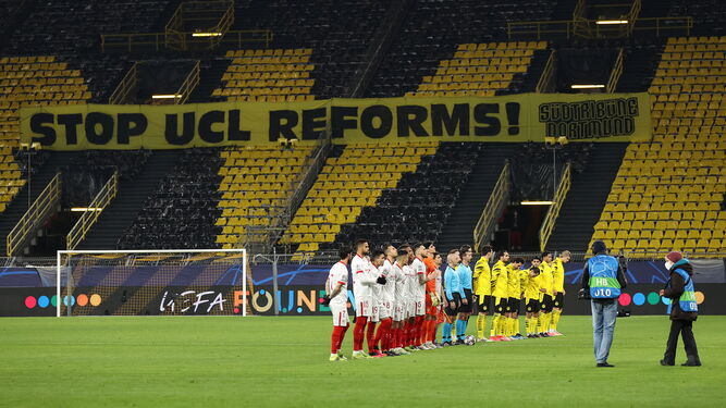 Los equipos de Sevilla y Borussia Dortmund, con una pancarta de fondo contra las reformas de la Champions.