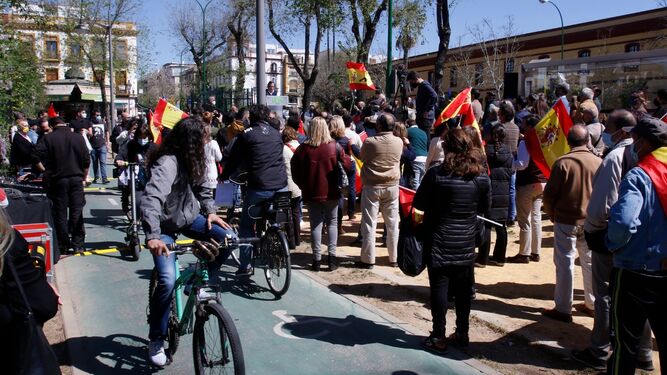 Un ciclita observa a su paso por el carril bici el acto convocado por Vox frente a la Diputación de Sevilla.