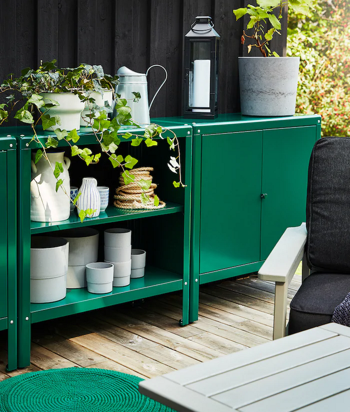 Un mueble para la terraza en color verde con detalles en blanco y acompañado de macetas.