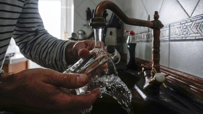 Un cliente de Emasesa lava un vaso de cristal en un grifo de la cocina.