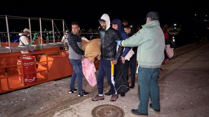 Miembros de la Cruz Roja, Guardia Civil y Salvamento Marítimo ayudan a un inmigrante su llegada al puerto de Motril.