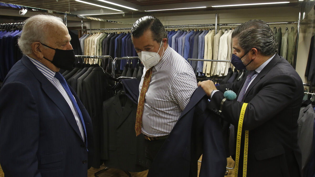 José Cañete y su hijo José María prueban una chaqueta a un cliente.