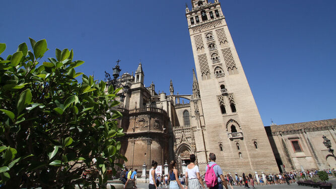 Un grupo de turistas junto a la catedral y la Giralda.