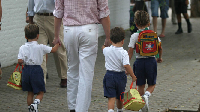 Un padre lleva a sus tres hijos al colegio.