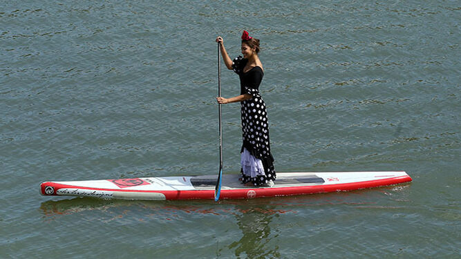 Ibis María Palomo vestida de flamenca practicando paddle surf por el Guadalquivir.