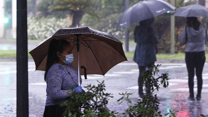 Una joven se protege de la lluvia con un paraguas.