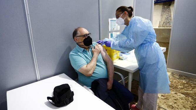 Una enfermera vacuna  a un hombre en el Palacio de Ferias de Málaga