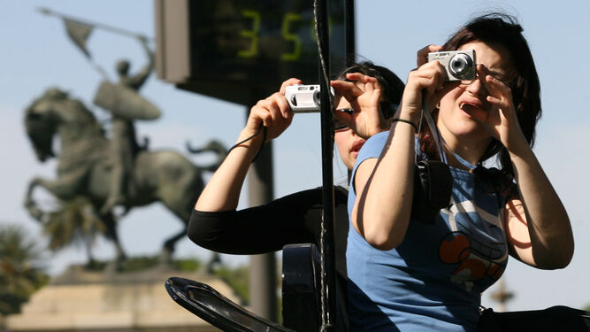Dos turistas fotografían el termómetro de El Prado de San Sebastián marcando 35 grados.