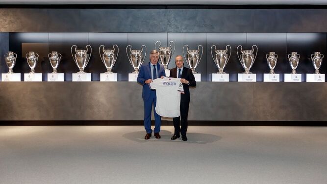 Ancelotti posa junto a Florentino Pérez con la camiseta madridista delante de las Copas de Europa.