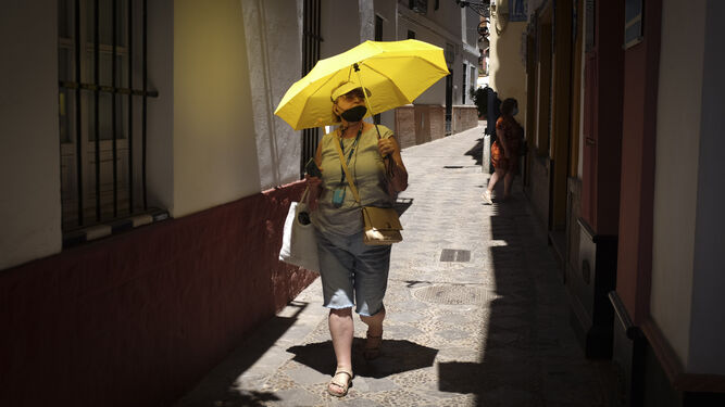 Turistas se cubren del sol con un paraguas en el barrio de Santa Cruz.