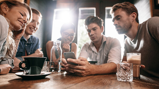 Grupo de amigos atentos a la pantalla de un smartphone.