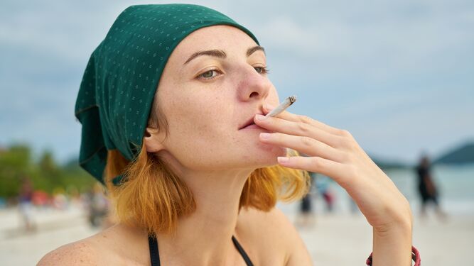 Mujer fumando en la playa.