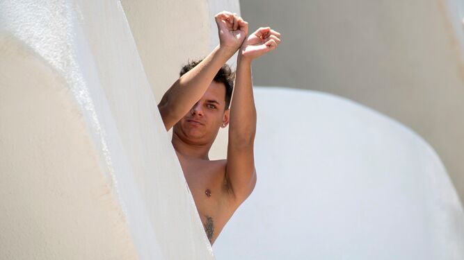 Un joven gesticula que está prisionero desde el balcón del hotel de Baleares donde está aislado.