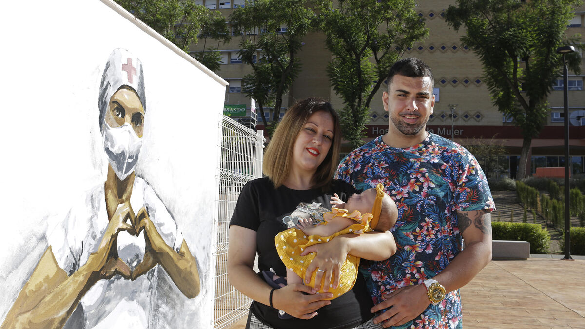 Miriam junto a su pareja y la pequeña Suhaila junto al mural en Homenaje a la Enfermería en el Hospital de la Mujer.