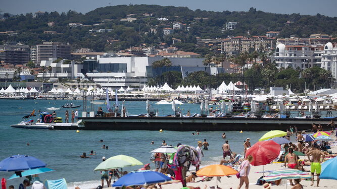 La playa de Cannes llena de veraneantes con el Palacio de Festivales al fondo.