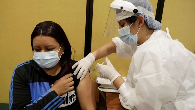 Una mujer recibe una vacuna por parte de una sanitaria